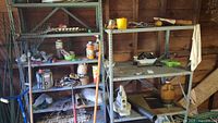 Two metal shelving units in a wooden shed with various items on shelves, including containers, tools, and gardening supplies.