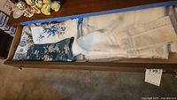Drawer with folded napkins, tablecloths, placemats, and apron with floral embroidery and lace