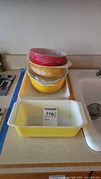 Wide view showing stacked pink and yellow Pyrex pieces on counter