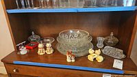 Full display of vintage glass serveware, salt and pepper shakers arranged on wooden shelf