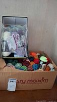 Box containing many skeins of yarn in assorted colors, some packaged, some loose.