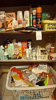 Photo of a cupboard shelf with personal care bottles including Rave Soft Curl Wave cream, Moisture Renewal lotion, various sprays, foot powder, and a basket.