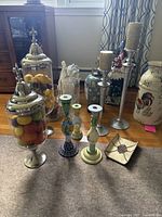 Wide view of entire assembly including apothecary jars, ceramic candlesticks, silver candle holders, roosters vases, small ceramic dish, and glass vases
