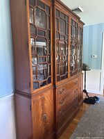 Side angled view of mahogany china cabinet showing glass-front doors, drawers, and lower cabinets