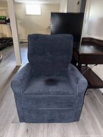 Front view of blue velour electric recliner chair showing cushioned armrests, seat and back, with a slight mark on the seat cushion.