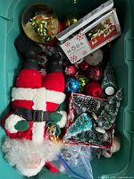 Photo of one bin showing plush Santa figure, Christmas tree ornaments, miniature bottle brush trees, and assorted baubles.