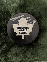 Top side of the puck showing the Toronto Maple Leafs logo and Dion Phaneuf autograph in silver marker.