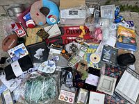 Photo showing a wide variety of miscellaneous items including sports memorabilia, collectible coins, home décor and accessories spread out on the ground.