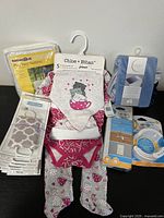 Photo showing baby clothes, bib, play yard netting, outlet covers, childproofing kit and changing pad cover all new in packaging or with tags.