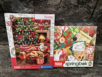 Photo showing two sealed 1000-piece Christmas puzzles side by side: Clementoni and Springbok brand boxes.