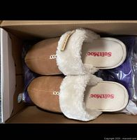 Top view of the chestnut brown SoftMoc slippers with white faux fur lining inside the box.