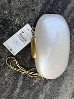 Full outer view of white glossy clamshell purse with attached price tag and gold chain strap.