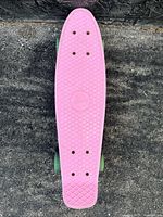 Top view of pink pennyboard skateboard deck showing textured grip pattern.