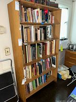 Front right angled view of the tall wood bookcase filled with books on shelves.