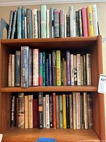 Three-shelf wooden bookcase filled with various hardcover books