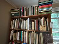 Three-shelf wooden bookcase filled with cloth-bound hardcovers and slipcased volumes