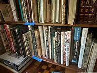Image showing a wood shelf with a variety of books, titles visible include 'The Passport,' 'A Vanished World,' and photography and poetry books.