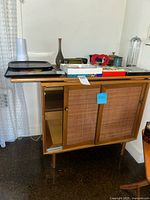 Front view of cabinet showing wood top, cane doors and tapered legs