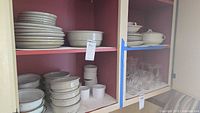 Shelves with stacked plates, bowls, cups and ramekins.