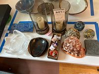 Overview photo showing some enamel dishes, glass paperweights, shells, candleholders, and enamel pins