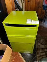 Front view of green Bisley metal file cabinet, showing open top slot, middle drawer, and bottom locked compartment.