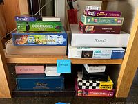 Photo showing stacked board games and puzzles including Codenames Duet, Carcassonne, Hanabi, Jaipur, Five Crownes, Tokado, Ravensburger puzzles, Scrabble, and chess.