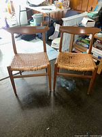 Front view of both chairs side by side showing woven cane seats, one seat torn
