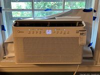 Front view of the white Midea portable air conditioner with digital display showing temperature 68 and control buttons.