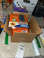 Cardboard box containing multiple packs of Terro Multi-Surface Roach Baits and other pest control supplies.