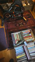Full view of the area rug partially under a stationary bike and near boxes of books on a wooden floor, showing overall condition and style.