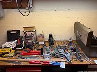 Craftsman toolbox and assorted hand tools including clamps, wrenches, hand plane, hacksaw, and power tools on table