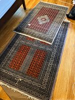 Two vintage area rugs placed on hardwood floor showing full rug designs and sizes.