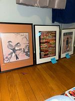 Three framed wall art prints placed side by side on floor: Asian birds on branch, sushi collage, Irving Berlin vintage print