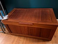 Front view of rectangular wooden chest with slatted panels and lid closed