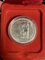 Obverse side of the 1958 Canadian Silver Dollar showing the totem pole design with inscriptions and housed in a clear protective capsule inside a red velvet-lined box.