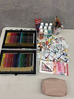 Wide view of all art supplies including colored pencils, paints, bottles, and brushes