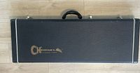 Closed black Charvel hard case with gold logo, rectangular shape with handle and metal latches.