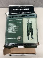 Front and side view of the box for green chest waders pants with boots and adjustable suspenders.