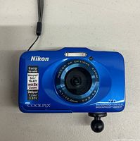 Front view of blue Nikon Coolpix S31 camera showing lens markings and certification labels on front.