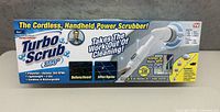 Photo of the front side of the Turbo Scrub 360 box showing product branding, features, and before/after cleaning illustrations.