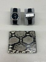 Front view of the two watches and snakeskin wallet showing details and materials.