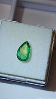 Pear-shaped emerald in white foam display box, top-down view