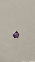 Photo of natural purple sapphire pear shaped with checkerboard cut on both sides.
