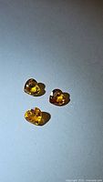 Three heart-shaped orange yellow sapphires with visible facets and high clarity.