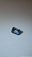 Single natural Swiss blue topaz gemstone, emerald cut, photographed on a plain background showing color and clarity.