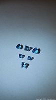 Image showing seven loose natural Swiss blue topaz gemstones of various cuts on a plain white surface under lighting.