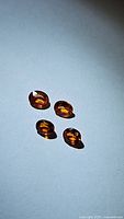 Four oval cut Imperial sapphires laid on a flat surface showing their oval shape and vivid orange color.