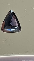 Close-up of deep navy blue trillion cut spinel, showing facets and color.
