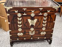 Front view of wooden cabinet showing butterfly metal hinges, locks, and decorative hardware on the door panels and frame