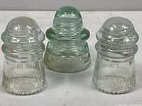 Group photo of the three Hemingray glass insulators showing sizes, shapes, and clear glass material.